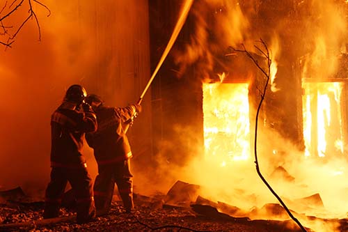 Card do curso perícia em incêndio - Perícia Expert. Página home. Na imagem tem dois bombeiros apagando um incêndio